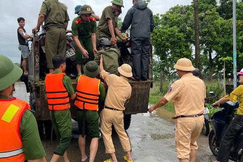 Lực lượng Cảnh sát giao thông giúp dân tham gia giao thông an toàn khi đi qua đoạn đường ngập nước