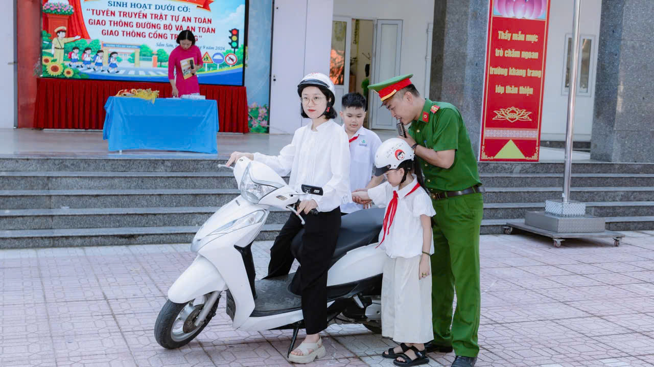 Cán bộ Công an phường hướng dẫn cách đội mũ bảo hiểm đúng quy định cho học sinh