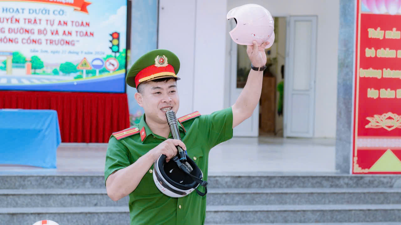 Cán bộ Công an phường hướng dẫn cách đội mũ bảo hiểm đúng quy định cho học sinh
